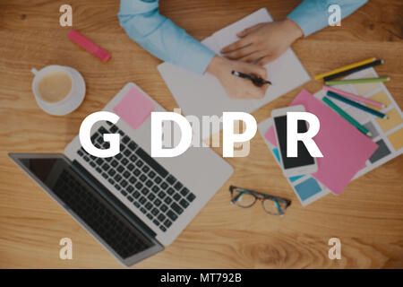 Top view of a blurred manager writing down personal data protection rules for his employees on a wooden table with laptop. GDPR concept Stock Photo
