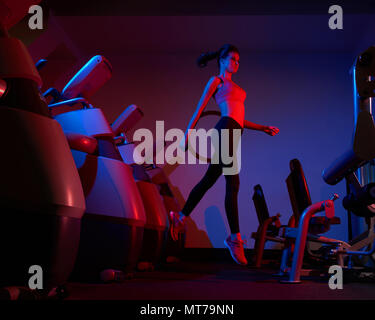 Slim woman jumping between rows of exercise machines Stock Photo
