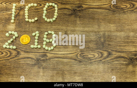 ICO 2018 text and golden bitcoin formed from marshmallow candies on wooden background Stock Photo