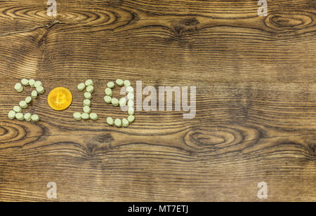 golden bitcoin and marshmallows forming 2019 text on wood. Stock Photo