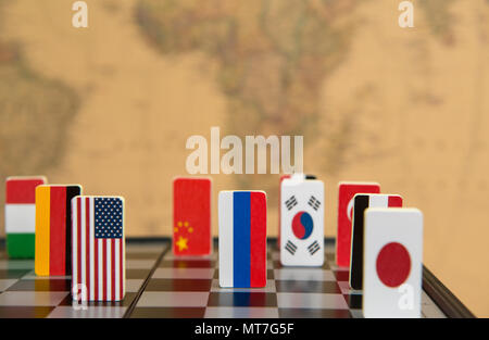 symbols of countries on the chessboard against against the background the political map of the world. Conceptual photo, political games. Stock Photo