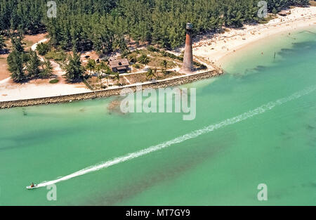 This aerial views shows how the historic 1825 lighthouse in Bill Baggs Cape Florida State Park looked in 1976 prior to its restoration when the brickwork was covered with white stucco at the south end of Key Biscayne in Miami-Dade County, Florida, USA. A navigational beacon atop the landmark lighthouse was relit in 1996 in celebration of Miami's centennial. To the left are the living quarters of the lighthouse keeper that have become a maritime museum. To the right is a stretch of beautiful white sand beach that is a main attraction for residents and visitors to Miami. Historical photo. Stock Photo