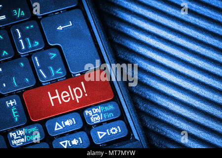 Close up of computer laptop keyboard with red button Help concept and copy space. Idea of IT support, computer assitance, advice and technology aid. Stock Photo