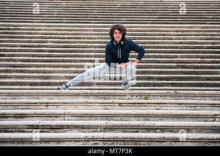 Handsome young sportsman stretching and warming-up for training on staircase Stock Photo