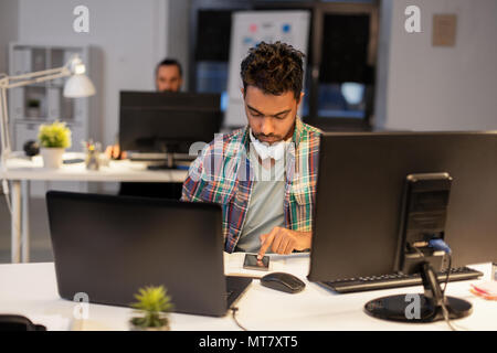 creative man with smartphone at night office Stock Photo