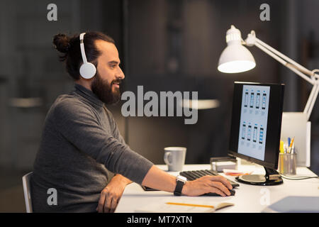 creative man in headphones working at night office Stock Photo