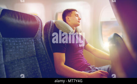 young man sleeping in plane with travel pillow Stock Photo