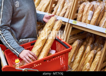 Buyer with bread baguettes with a grocery basket in the store Stock Photo