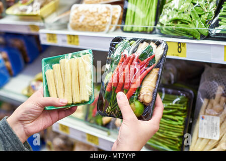 Buyer chooses fresh vegetables pepper, corn in shop Stock Photo