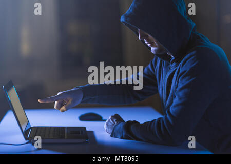 hacker pointing at laptop computer in dark room Stock Photo
