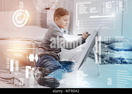 Diligent pupil using modern technologies while doing his homework Stock Photo