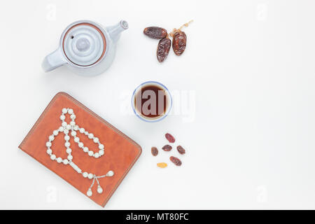 Table top view aerial image of decoration Ramadan Kareem holiday background.Flat lay dates with white rosary & cup tea.The holy book of Koran on moder Stock Photo