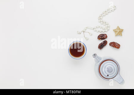 Table top view aerial image of decoration Ramadan Kareem holiday background.Flat lay dates with white rosary & cup tea.Halal meal set for fasting is o Stock Photo