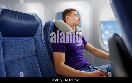 Young Man Sleeping In Plane With Travel Pillow Stock Photo