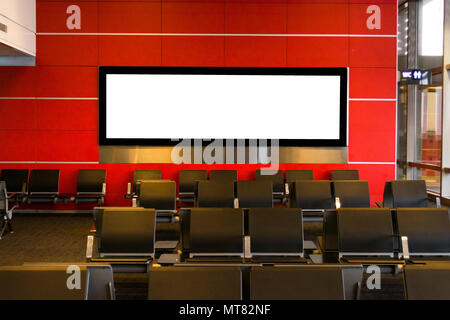Blank billboard on modern red wall in airport with seating, Stock Photo