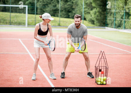 Young woman with male insructor playing tennis Stock Photo