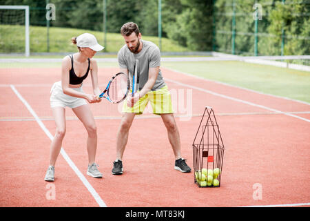 Young woman with male insructor playing tennis Stock Photo