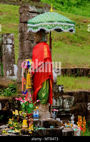 Buddha statue and offerings in the sanctuary of Vat Phou, Champasak, Southern Laos Stock Photo