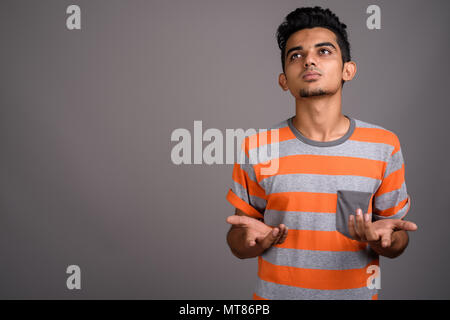 Young Indian man against gray background Stock Photo