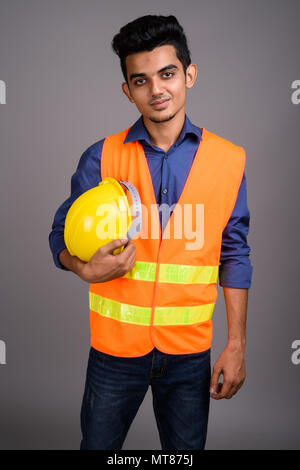 Young Indian man construction worker against gray background Stock Photo