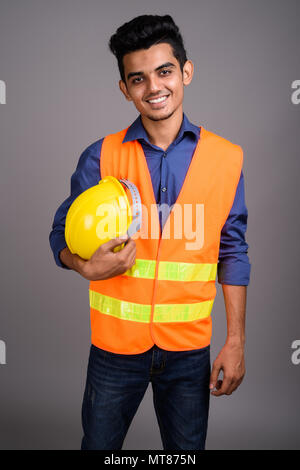 Young Indian man construction worker against gray background Stock Photo
