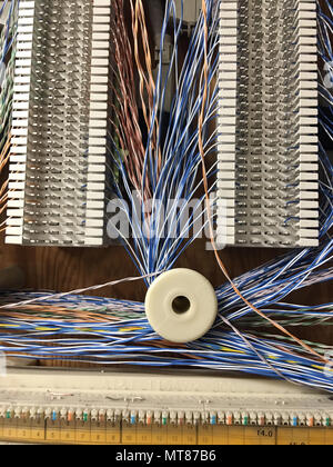 Small diameter multi color wires run around spools mounted to boards in the phone room Stock Photo