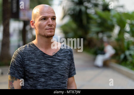 Young handsome bald man thinking outdoors Stock Photo