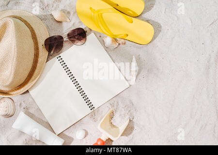 Top view of sandy beach with glasses and summer accessories. Background with copy space and visible sand texture. Border composition made of towel Stock Photo