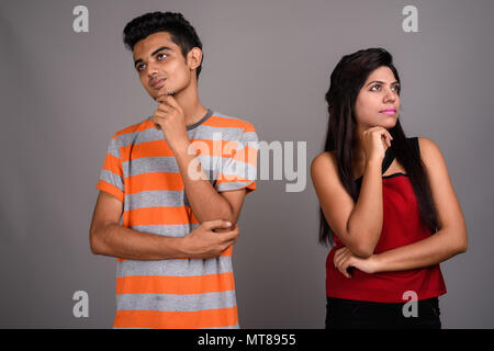 Young Indian man and young Indian woman together against gray ba Stock Photo