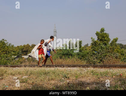 Mandalay, Myanmar - Feb 22, 2016. Homeless boys walking on rail track at countryside in Mandalay, Myanmar. Stock Photo