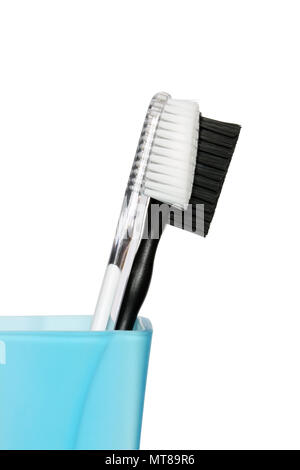 Black and white toothbrushes in blue glass. Isolated with clipping path Stock Photo