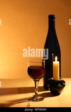 Wineglass near bottle of red wine and candle on nice brown background Stock Photo