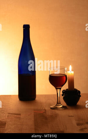 Wineglass near bottle of red wine and candle on nice brown background Stock Photo