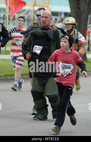 U.S. Air Force Senior Master Sgt. Bill Kennedy, a 119th Wing Explosive Ordnance Disposal (EOD) technician, North Dakota Air National Guard, runs the 5K Hero Run event wearing an 88 pound ‘bomb protection suit’ at the Fargo Marathon, Fargo, N.D., May 19, 2017. The Fargo Marathon weekend running events have a hero theme because Armed Forces Day occurs during the events, Saturday, May 20. (U.S. Air National Guard Photo by Senior Master Sgt. David H. Lipp/Released) Stock Photo