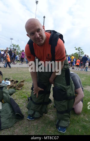 U.S. Air Force Senior Master Sgt. Bill Kennedy, a 119th Wing Explosive Ordnance Disposal (EOD) technician, North Dakota Air National Guard, puts on his 88 pound bomb protection suit as he prepares to run the 5K Hero Run event wearing the suit at the Fargo Marathon, Fargo, N.D., May 19, 2017. The Fargo Marathon weekend running events have a hero theme because Armed Forces Day occurs during the events, Saturday, May 20. (U.S. Air National Guard Photo by Senior Master Sgt. David H. Lipp/Released) Stock Photo