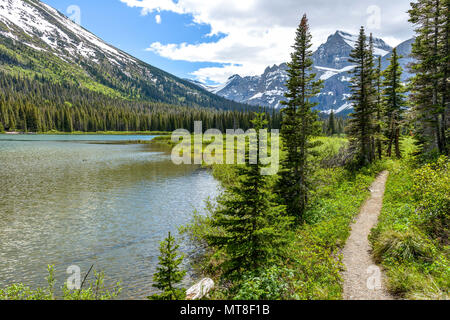 Mountain Lake Trail - A spring view of a hiking trail along Lake Josephine at the base of Mount Gould in Many Glacier of Glacier National Park, USA. Stock Photo