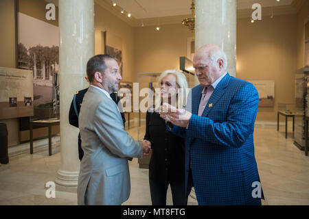 Micheal Migliara (left), director of events and ceremonies, Arlington National Cemetery; presents an Arlington National Cemetery coin to Terry Bradshaw (right), representative of United Service Organization (USO) Metro; and his wife, Tammy Bradshaw (center) in the Memorial Amphitheater Display Room at Arlington National Cemetery, Arlington, Virginia, May 11, 2018. Bradshaw participated in an Army Special Honors Wreath-Laying at the Tomb of the Unknown Soldier during his visit. (U.S. Army photo by Elizabeth Fraser / Arlington National Cemetery/ released) Stock Photo