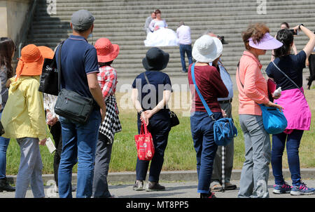 28 May 2018, Germany, Berlin: A group of tourists from Korea in the Lustgarten watches as a wedding couple pose for photos on the steps of the Altes Museum. Photo: Wolfgang Kumm/dpa Stock Photo