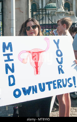 Belfast, Northern Ireland. 28/05/2018 - A woman holds a placard saying 'Mind your own uterus!'  Around 500 people gather at Belfast City Hall to call for the decriminalisation of abortion in Northern Ireland.  It comes the day after a referendum held in the Republic of Ireland returned a substantial 'Yes' to removing the 8th amendment to the constitution, which gives equal right of life to both the mother and baby, effectively banning abortion in all circumstances. Stock Photo