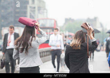London UK. 29th May 2018. Commuters returning to work after the  hot  bank holiday weekend shelter under umbrellas from the rain on Westminster Bridge Credit: amer ghazzal/Alamy Live News