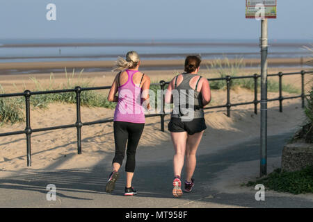 Woman running on the seafront promenade at Crosby, Liverpool.  29th May, 2018. UK Weather:  Bright summer day on the north-west coast as local residents and holidaymakers take early morning exercise on the coastal path and Merseyside beach. The beach is festooned with Spring Bank Holiday litter with overflowing bins and garbage blowing in the breeze. The Sefton council containers clearly inadequate for the amount of plastic waste. Credit: MediaWorldImages/AlamyyLiveNews. Stock Photo