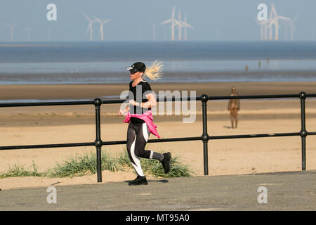 Woman running on the seafront promenade at Crosby, Liverpool.  29th May, 2018. UK Weather:  Bright summer day on the north-west coast as local residents and holidaymakers take early morning exercise on the coastal path and Merseyside beach. The beach is festooned with Spring Bank Holiday litter with overflowing bins and garbage blowing in the breeze. The Sefton council containers clearly inadequate for the amount of plastic waste. Credit: MediaWorldImages/AlamyyLiveNews. Stock Photo