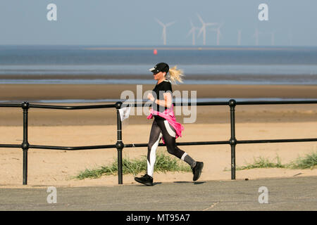 Woman running on the seafront promenade at Crosby, Liverpool.  29th May, 2018. UK Weather:  Bright summer day on the north-west coast as local residents and holidaymakers take early morning exercise on the coastal path and Merseyside beach. The beach is festooned with Spring Bank Holiday litter with overflowing bins and garbage blowing in the breeze. The Sefton council containers clearly inadequate for the amount of plastic waste. Credit: MediaWorldImages/AlamyyLiveNews. Stock Photo