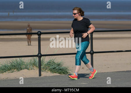 Woman running on the seafront promenade at Crosby, Liverpool.  29th May, 2018. UK Weather:  Bright summer day on the north-west coast as local residents and holidaymakers take early morning exercise on the coastal path and Merseyside beach. The beach is festooned with Spring Bank Holiday litter with overflowing bins and garbage blowing in the breeze. The Sefton council containers clearly inadequate for the amount of plastic waste. Credit: MediaWorldImages/AlamyyLiveNews. Stock Photo