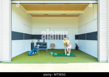 Dedicated golf coach using modern equipment while teaching a young woman Stock Photo