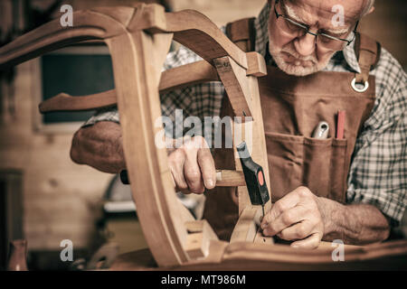 elderly carpenter builds a classic style chair Stock Photo