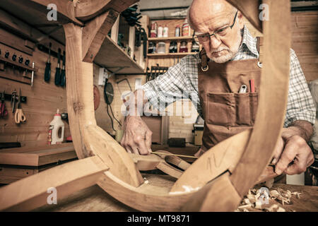 elderly carpenter builds a classic style chair Stock Photo