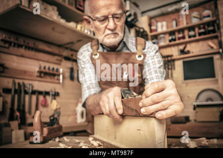 old carpenter uses a planer Stock Photo