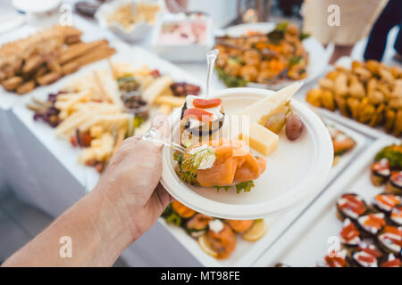 Man helping himself on Buffet of party outdoors taking food  Stock Photo