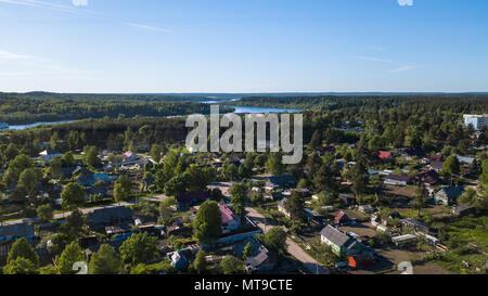 Russian village with wooden houses. Svir river and summer green forests of Leningrad region, Russia. Flying over roofs. Stock Photo